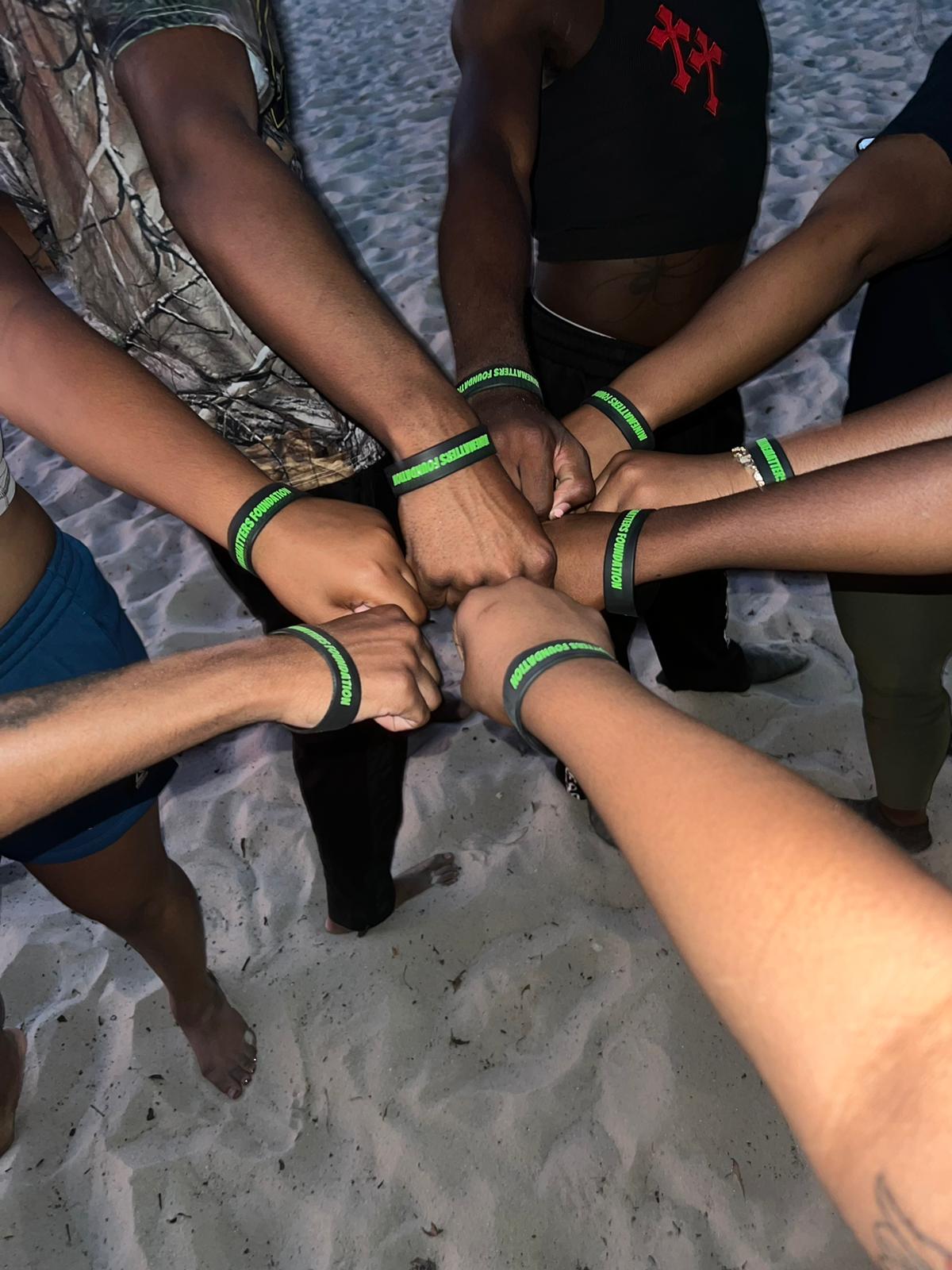 Hands joined in a circle, each wrist wearing a green awareness band
